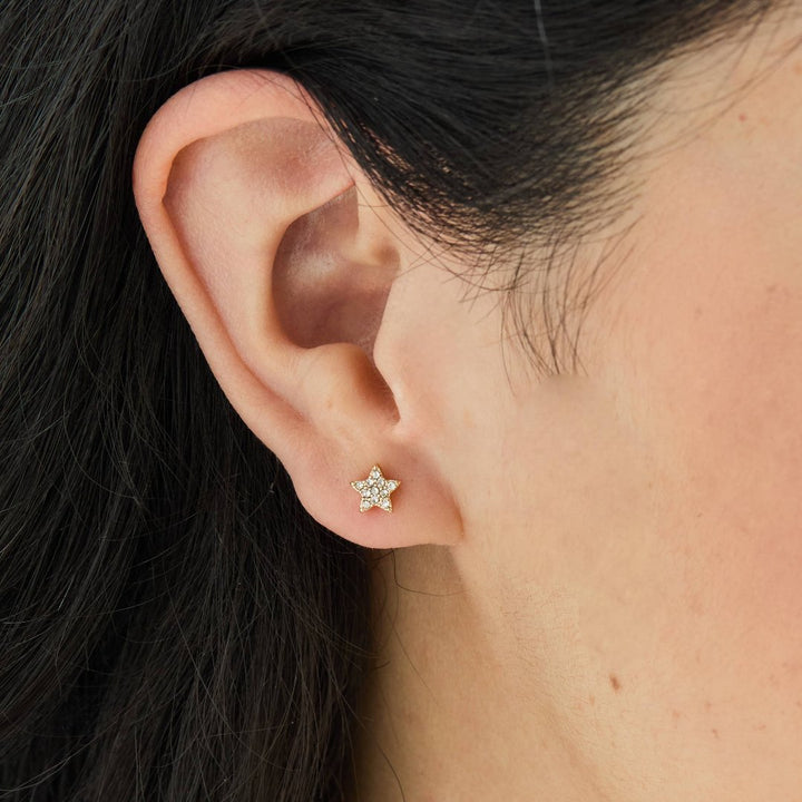 A set of gold stud earrings representing the days of the week. The earrings are arranged on a pink card with the words 