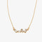 A gold necklace with several rectangular-shaped crystals on a pink card with the brand name 