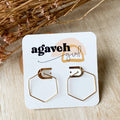 A pair of Agaveh Girl Gold Hexi Hoops, featuring a thin, gold wire hexagon design, displayed on a branded card with the text 'agaveh girl,' against a textured background with dried floral accents. The earrings are minimalist and geometric, available in Ottawa, Ontario, Canada.