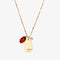 A gold necklace with a ruby stone pendant. The pendant also has the word 