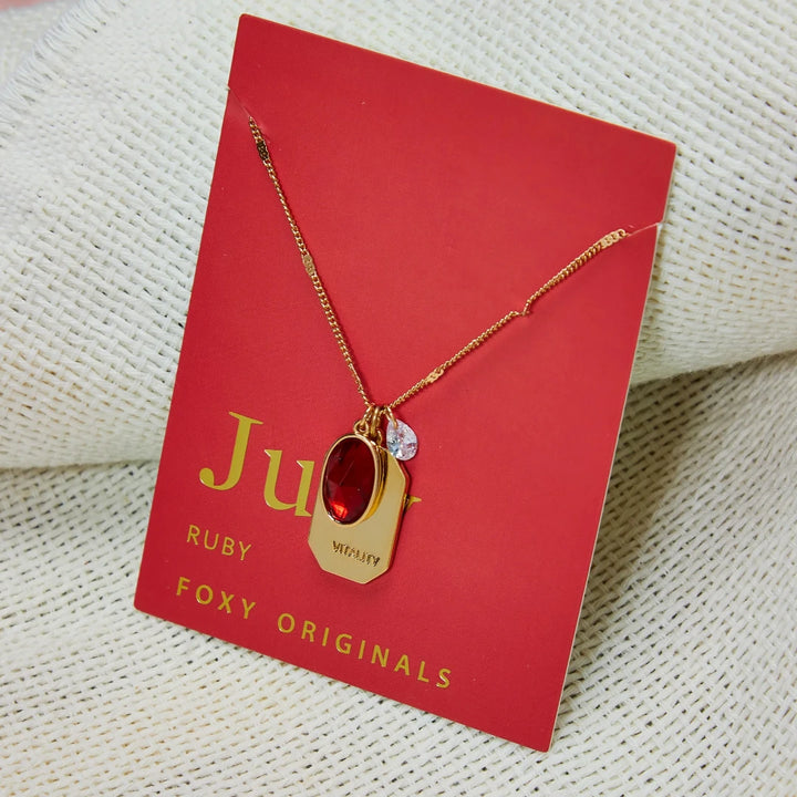 A gold necklace with a ruby stone pendant. The pendant also has the word 