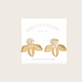 A pair of gold earrings with a leaf design. The earrings have a white, circular resin center with gold flecks. The leaves are attached to the center and can be detached.
