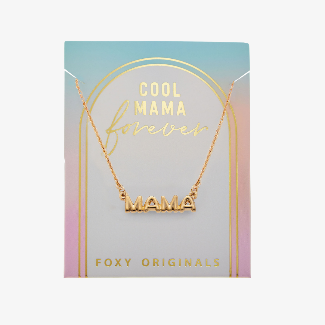 A gold necklace on a pink background. The necklace features a gold pendant with the word "MAMA" in bold letters. The text "COOL MAMA FOREVER" is printed on the background card, along with the brand name "Foxy Originals."