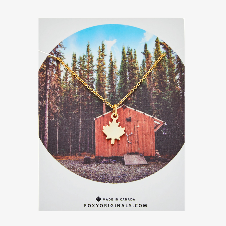 A gold necklace with a maple leaf pendant.