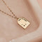 A gold necklace with a pendant shaped like an archway. The pendant has the words 