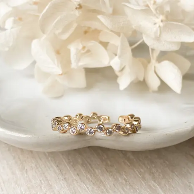 A 14k gold vintage scallop ring, featuring a beaded and scalloped design with small gemstones, displayed on a textured white surface with white floral accents. The ring is an open-style ring, available in Ottawa, Ontario, Canada.