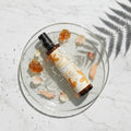 Skincare bottle with natural elements on a glass plate
