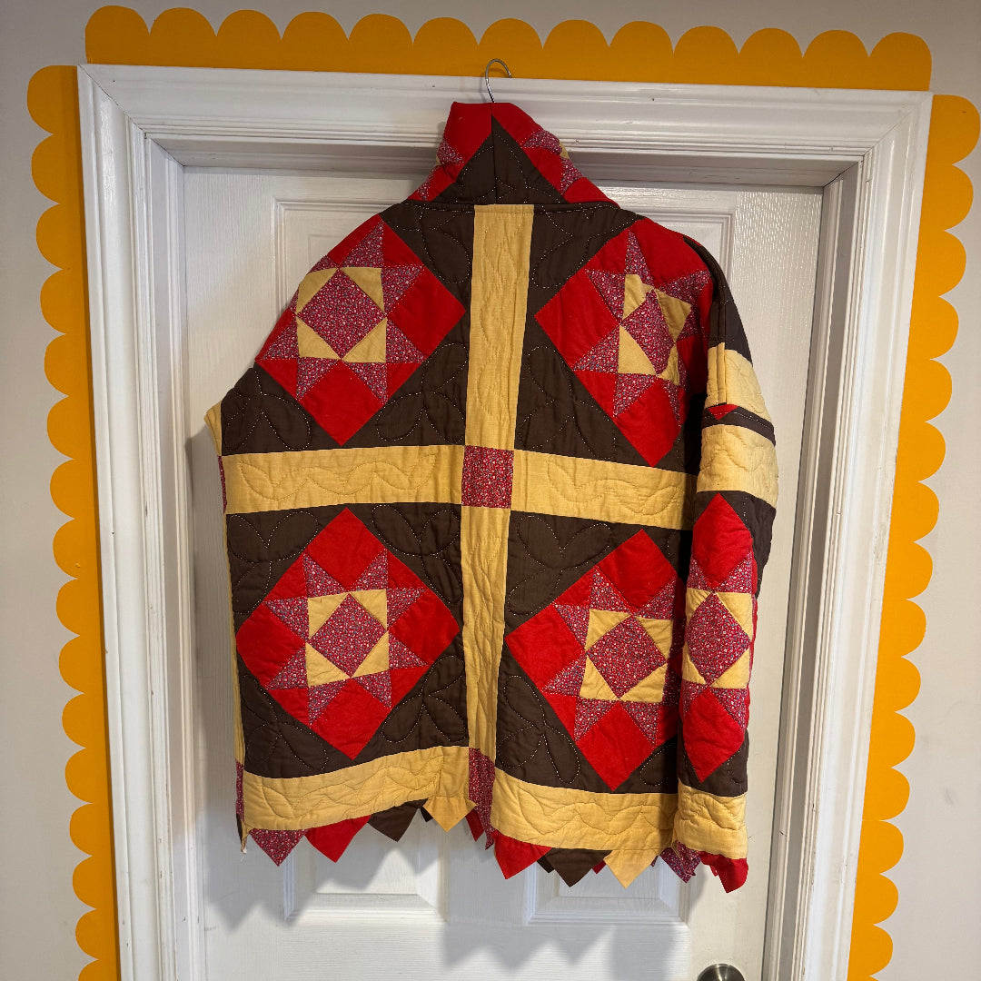 Quilt with red and brown geometric pattern draped over a white door with yellow trim.