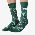 A pair of green crew socks featuring a fishing-themed pattern with illustrations of leaping fish, fishing rods, bobbers, and lures in shades of white, red, and black. One sock displays the text "GONE FISHING" in white letters. The cuff, heel, and toe of the sock are the same shade of green as the base.