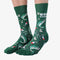 A pair of green crew socks featuring a fishing-themed pattern with illustrations of leaping fish, fishing rods, bobbers, and lures in shades of white, red, and black. One sock displays the text 