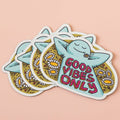 A blue, cartoon character with arms outstretched is lying on its back in a field of daisies. The text "GOOD VIBES ONLY" appears in bold, colorful letters below the character.
