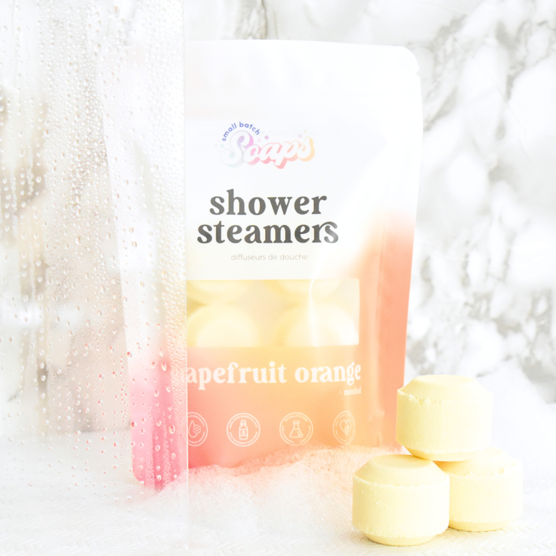 Pack of shower steamers labeled 'Pomegranate & Grapefruit' with steam in the background