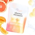 Grapefruit orange shower steamers with packaging and fruit slices on a white background