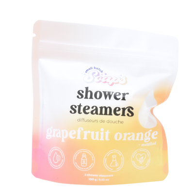 A white stand-up pouch for shower steamers. A clear window on the front reveals orange and pink steamers inside. The label features 