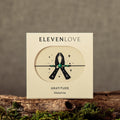 Product packaging for 'Eleven Love' with a black ribbon design on a textured surface.