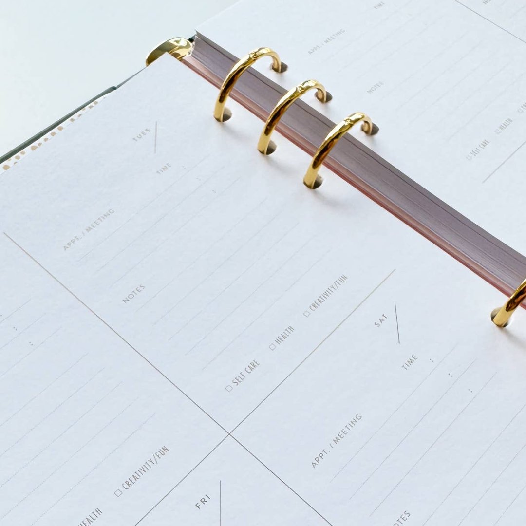 A black agenda with the phrase "It's Gonna Be A Great Year" written in colorful letters. The letters are outlined in gold and there are gold stars scattered around the text. The agenda has a purple elastic band.