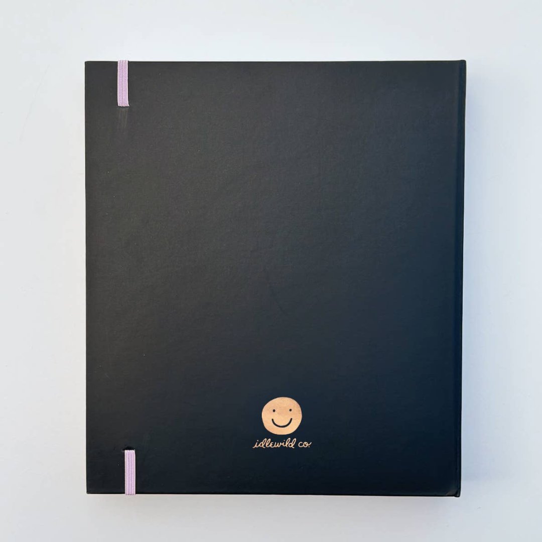 A black agenda with the phrase "It's Gonna Be A Great Year" written in colorful letters. The letters are outlined in gold and there are gold stars scattered around the text. The agenda has a purple elastic band.