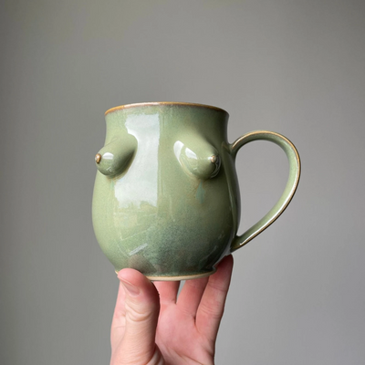 Green Boob Mug, a large coffee cup with large handle with 3 dimensional breats on the front in a green colour.