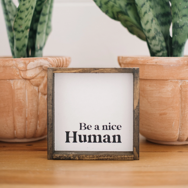 A framed square wooden sign with the text 