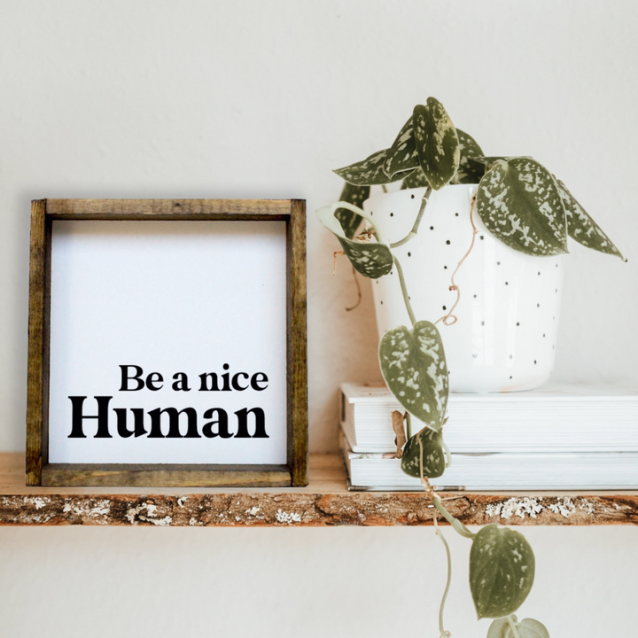 A framed square wooden sign with the text 