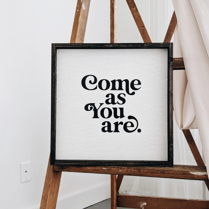 A framed square wood sign with the text 