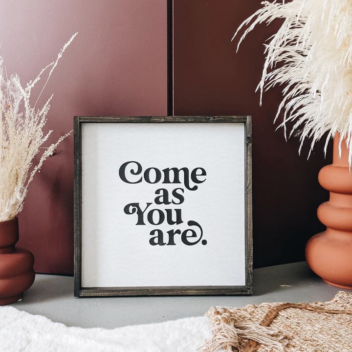 A framed square wood sign with the text 