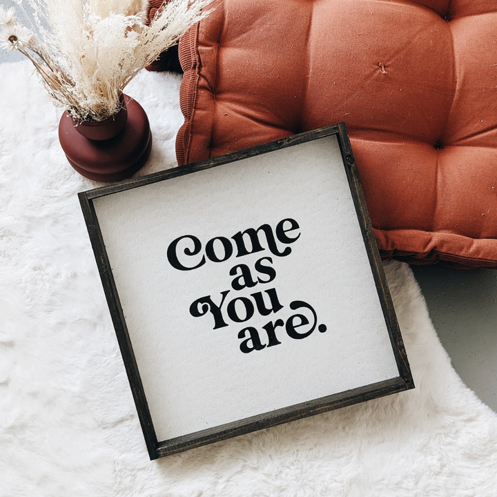 A framed square wood sign with the text 