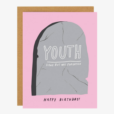 A pink greeting card with a brown envelope. The card features a gray tombstone with the word 
