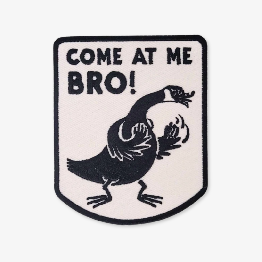 An iron-on patch featuring a cartoon Canada Goose in an aggressive stance with raised wings, accompanied by the text 'COME AT ME BRO!' in bold black letters on a white background with a black border. This funny and novelty patch is likely popular in Ottawa, Ontario, Canada, due to the presence of Canada Geese.