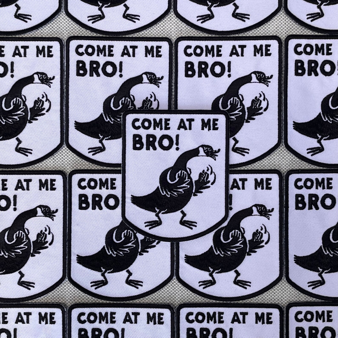 An iron-on patch featuring a cartoon Canada Goose in an aggressive stance with raised wings, accompanied by the text 'COME AT ME BRO!' in bold black letters on a white background with a black border. This funny and novelty patch is likely popular in Ottawa, Ontario, Canada, due to the presence of Canada Geese.