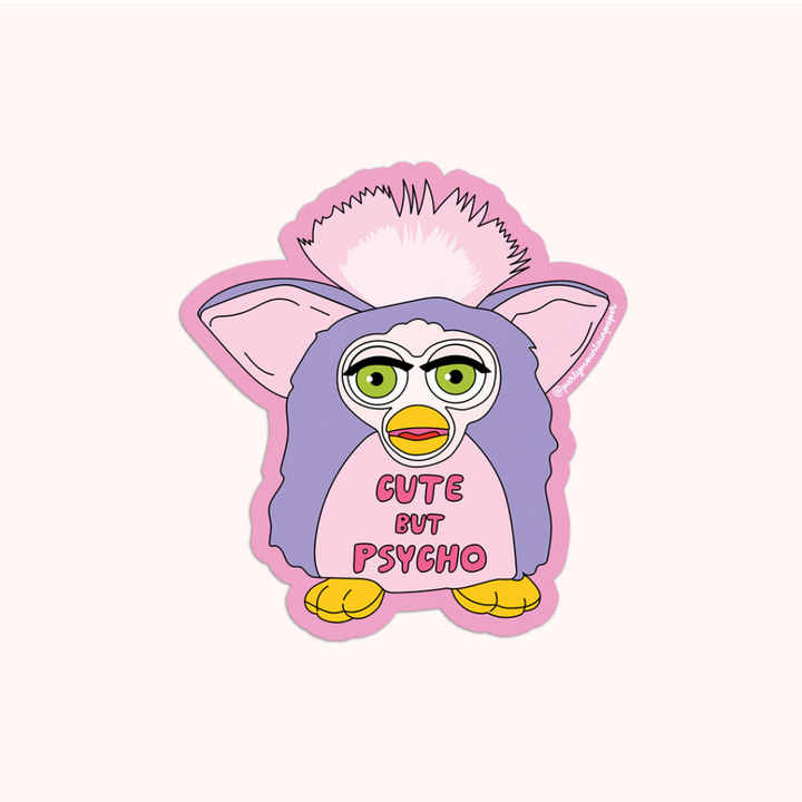 A pink sticker with a cartoon illustration of a Furby toy. The Furby has green eyes, a pink head, and a purple body. The text 