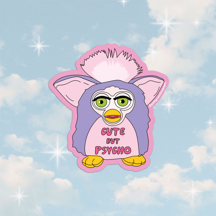 A pink sticker with a cartoon illustration of a Furby toy. The Furby has green eyes, a pink head, and a purple body. The text 
