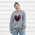 a grey sweatshirt with a large, heart-shaped patch. The patch features a Native American-inspired geometric pattern in shades of red, blue, and white.