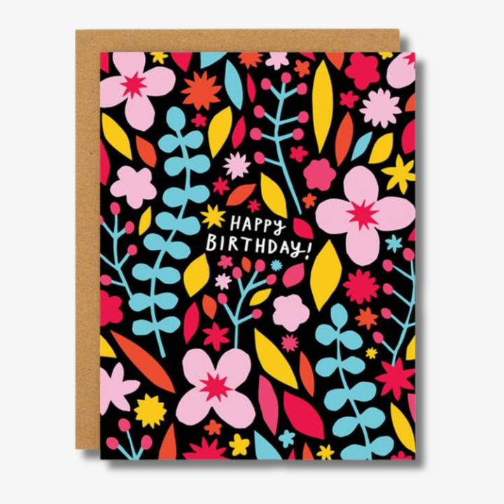Meadow Birthday Card: A vibrant floral birthday card featuring colourful flowers and leaves in pink, red, blue, yellow, and white. The central white text on a black background reads ‘Happy Birthday!
