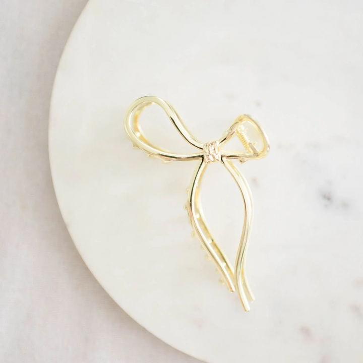 Gold Metallic Bow Clip, a claw clip in a gold metallic finish. Perfect for adding a feminine touch to any hairstyle.
