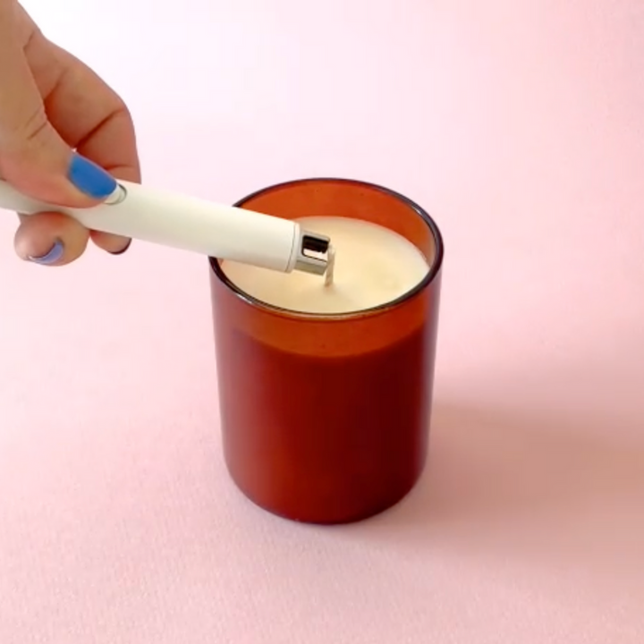 A DuoTone Flameless Lighter being used to light a candle.