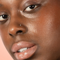 Red-dy or Not Lip & Cheek Tinted Balm, a liquid blush used on a black woman's eyes, cheeks and lips.