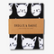 A black tea towel with a pattern of white cat faces. The cat faces are arranged in a grid-like pattern and vary in size and shape.