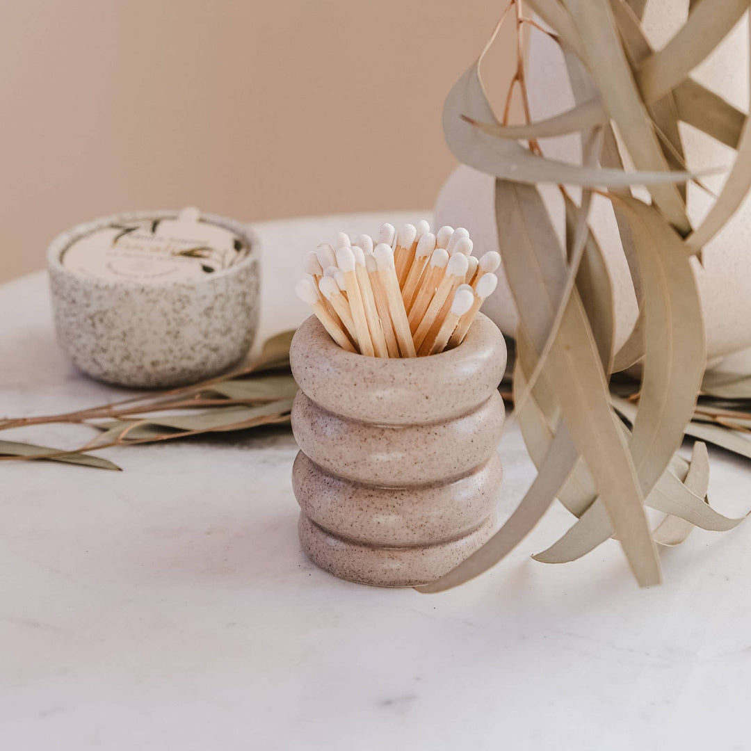 Stack of stone-like containers with a toothpick holder on a neutral background
