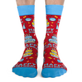 Red socks with 'Happy Birthday' and cake designs, worn by a person on a white background