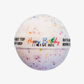 A round white bath bomb with colorful confetti speckles and a paper band reading 'Happy Birthday' and 'Bath Bomb Shop,' shown on a plain light background.