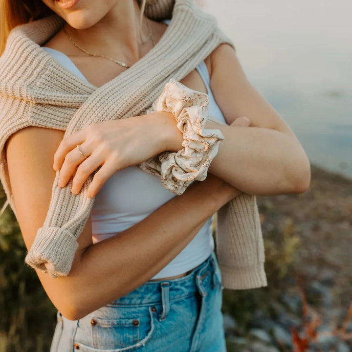 A cream-colored scrunchie with a floral pattern in brown.