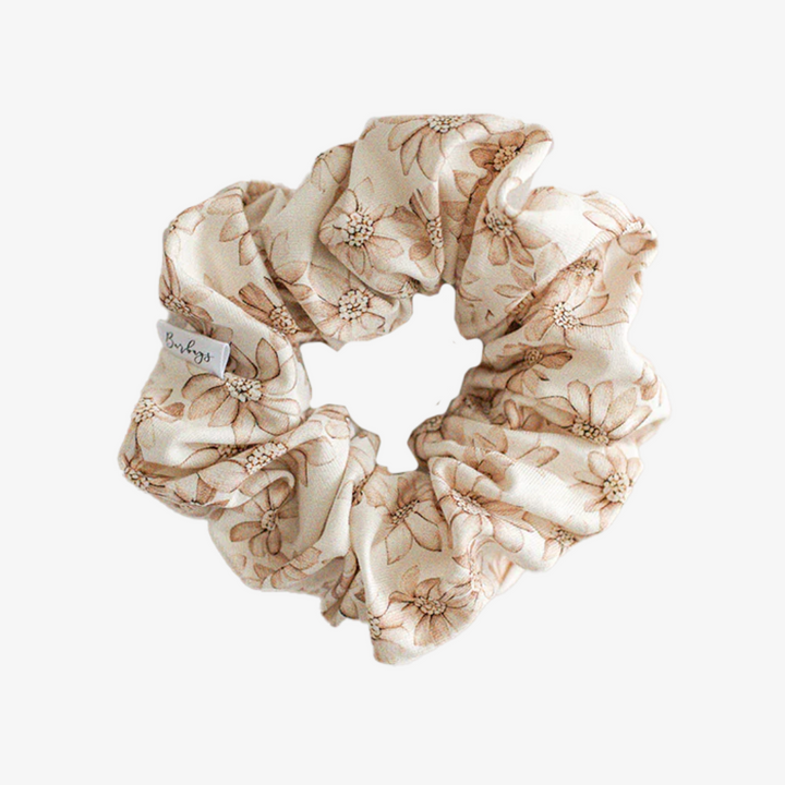 A cream-colored scrunchie with a floral pattern in brown.