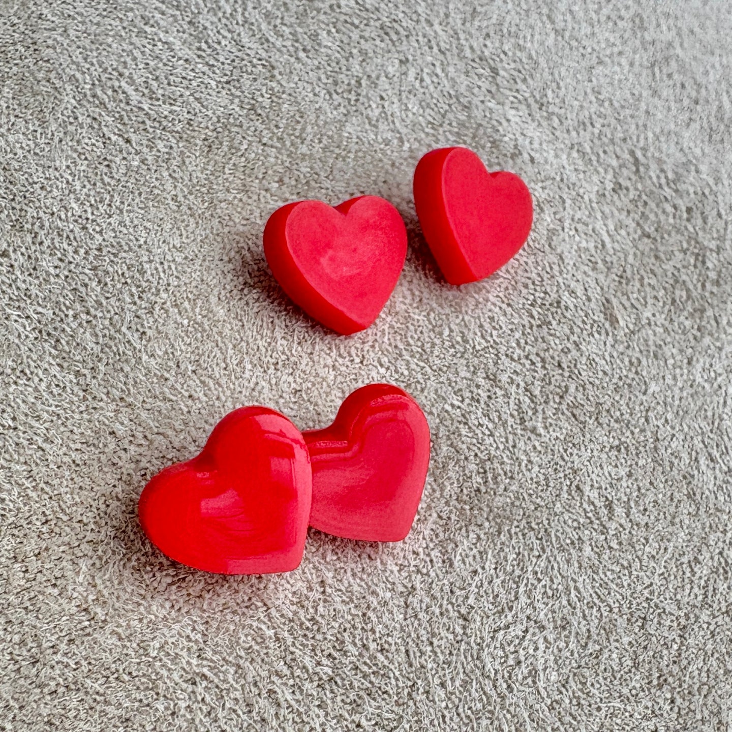 Red heart-shaped objects on a textured gray surface
