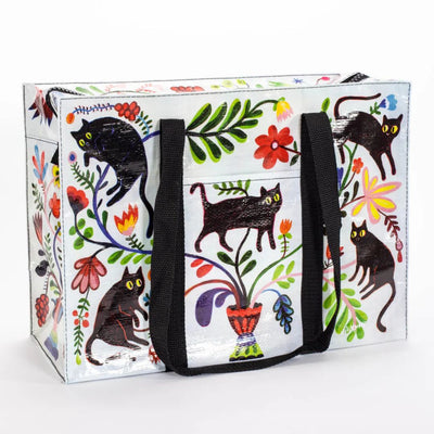 A rectangular shoulder tote bag with black handles, featuring a whimsical pattern of black cats, colourful flowers, and foliage against a white background.
