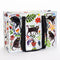 A rectangular shoulder tote bag with black handles, featuring a whimsical pattern of black cats, colourful flowers, and foliage against a white background.