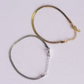 Two bracelets, one gold and one silver, on a light gray background