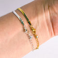 Close-up of a wrist wearing two gold and silver bracelets on a light background