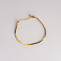 Gold bracelet on a light gray background