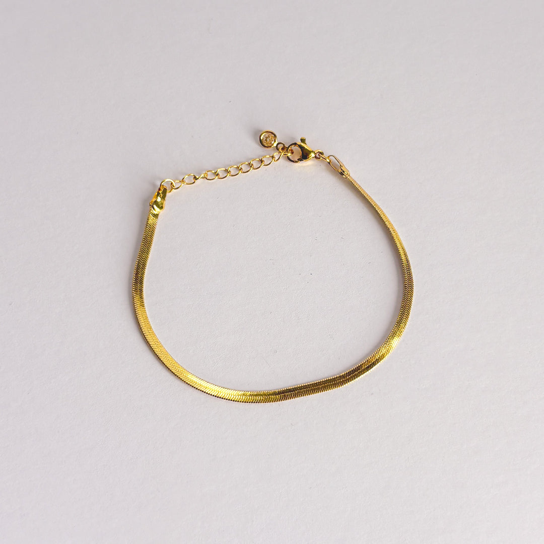 Gold bracelet on a light gray background